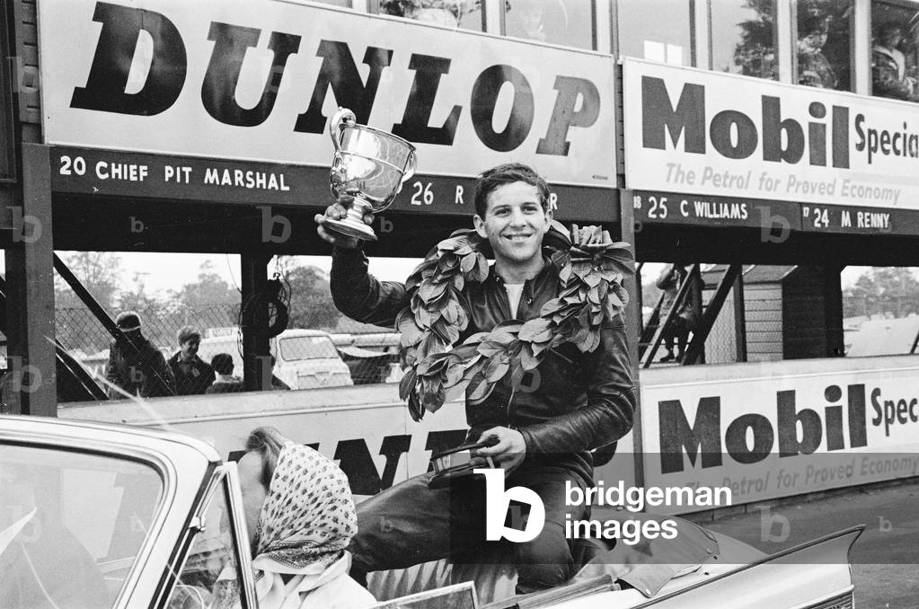 Motor Cycle Racing at Oulton Park. Phil Read celebrates with the trophy on a lap of honour after winning the British Junior Championship race. 7th July 1963 (b/w photo)
