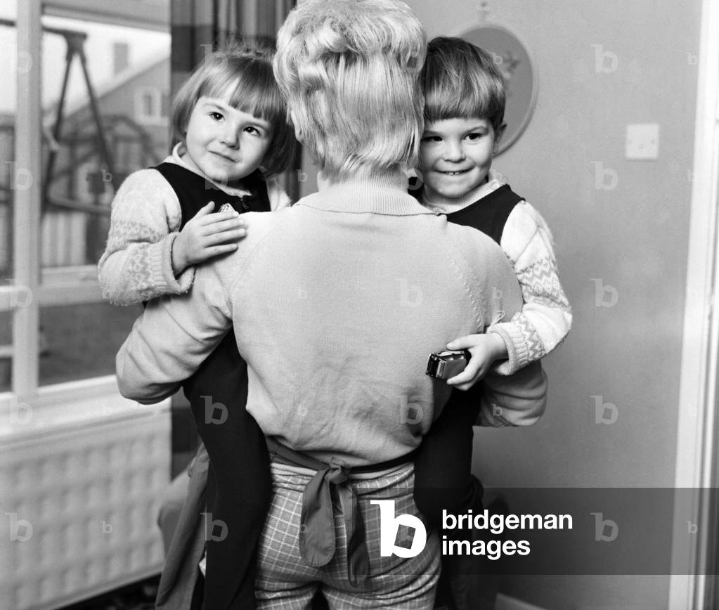 Young twins holding hands, running with happy expressions, October 1969 (b/w photo)