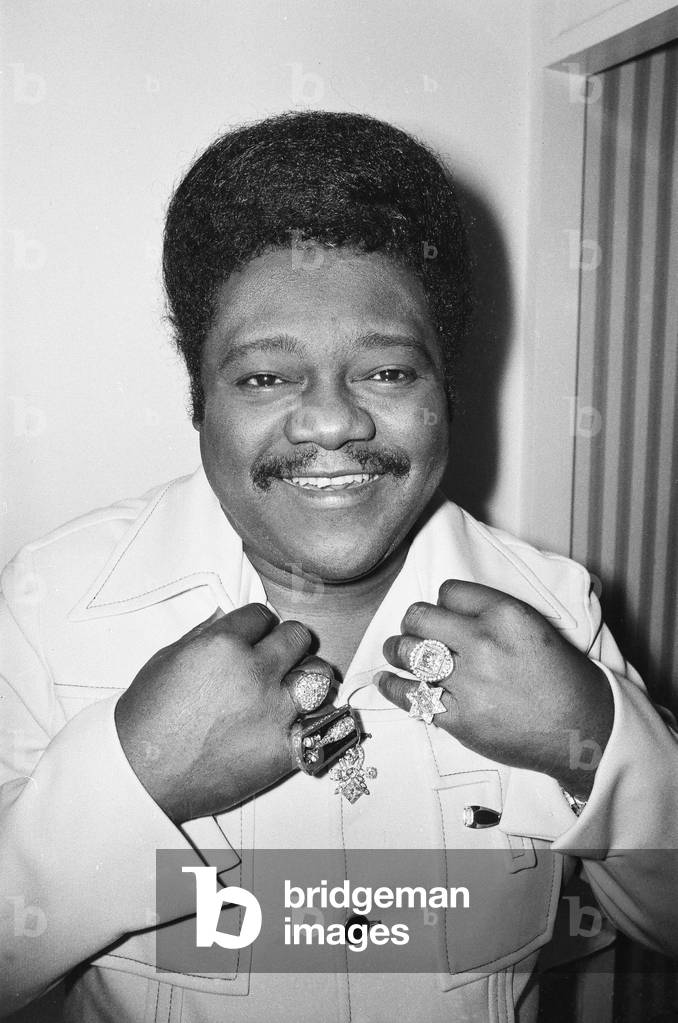 American rock and roll singer and musician Fats Domino shows off his diamond rings in his hotel suite, before his concert at the Victoria Theatre in London. 23rd March 1976 (b/w photo)