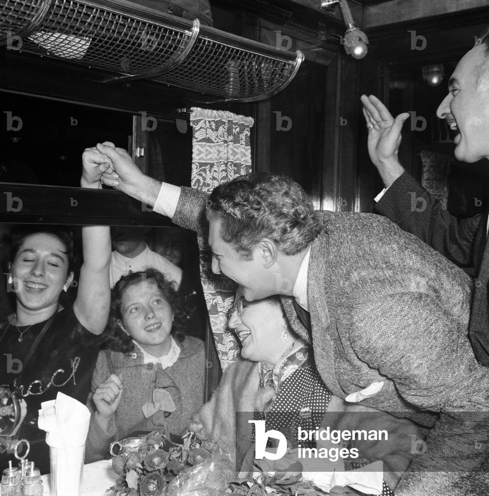 Liberace leaves Southampton cheered on by his fans. 15 year old Corinne Rodriguez of Stepney holds his hand through the train window. 25th September 1956.
