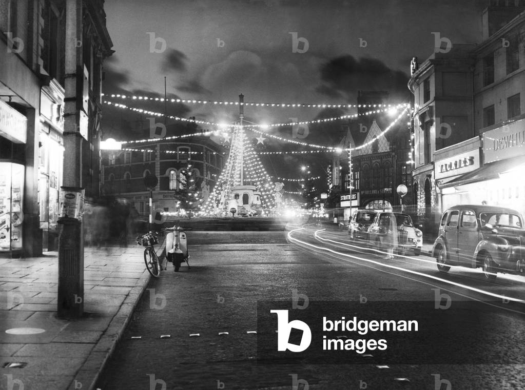 The Christmas lights at Charing Cross, Birkenhead are tested before the offical switch on, Liverpool, Merseyside. The central tableau on the roundabout carries the figures of the Flintstones cartoon characters. The image, taken on a time exposure, shows the track of various car lights 23rd November 1963 (b/w photo)