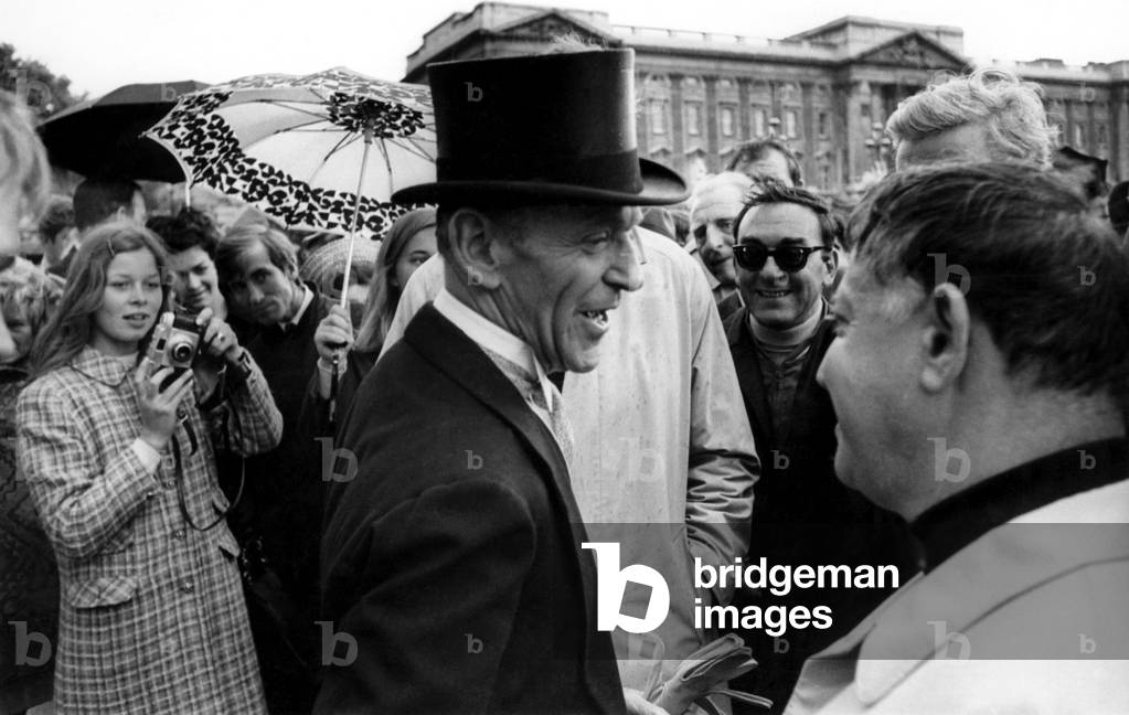 Fred Astaire returns the smiles of onlooker outside Buckingham Palace, during the final scene of 