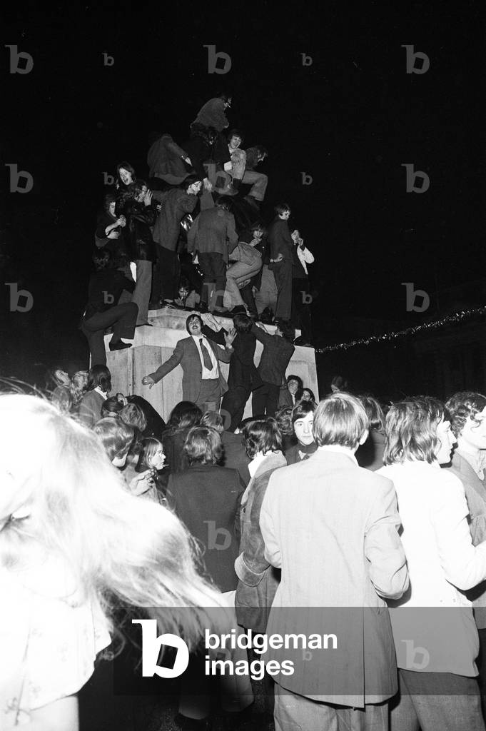 A happy crowd of young people greet the New Year in high-spirits in Broadgate, Coventry. But for one couple it's a much more personal occasion. 1st January 1973 (b/w photo)