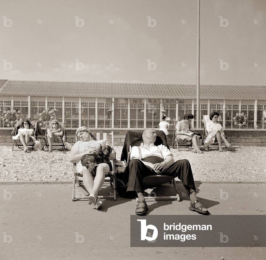 Butlins Holiday Camp at Bognor a couple sleeping in a deckchair with their dog, the promenade by the sea man wearing sandals and socks, June 1962 (b/w photo)