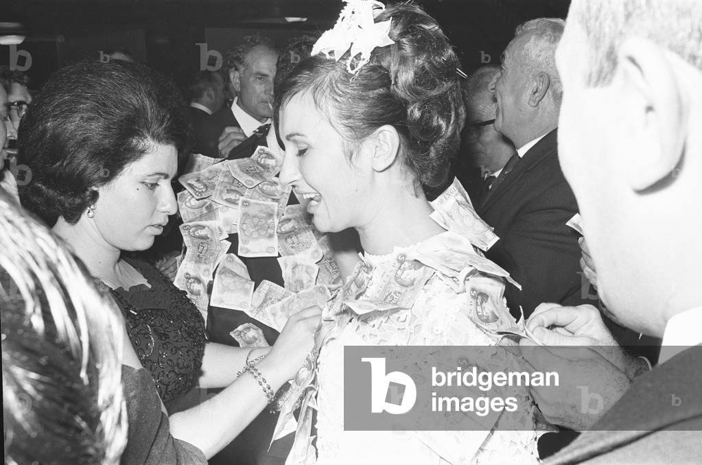 Elias Nicholas kisses his new bride and Katerina following the money dance at a traditional Greek wedding. Where gifts of money from their guests are pinned to the bride and groom. 23rd September 1967 (b/w photo)