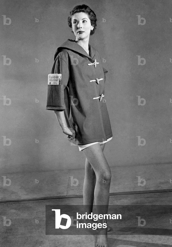 Clothing Beach. 
Woman wears duffel coat with handy pocket in the sleeve and miniskirt. 
April 1954