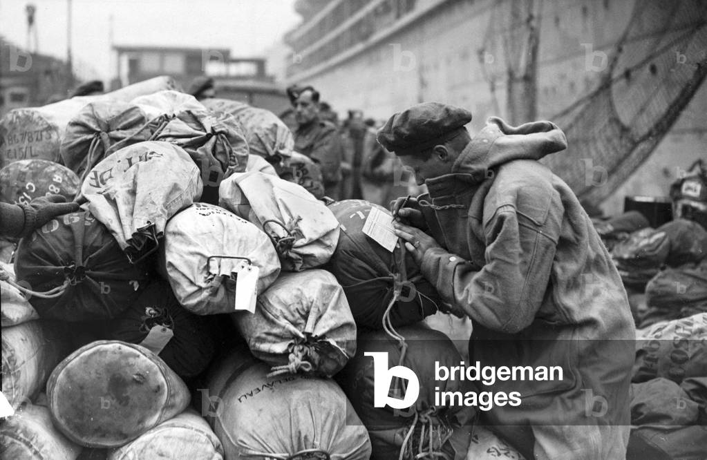 Soldier writes a farewell card home before embarking on a troopship bound for the Italian theatre. 25 February 1944 (b/w photo)