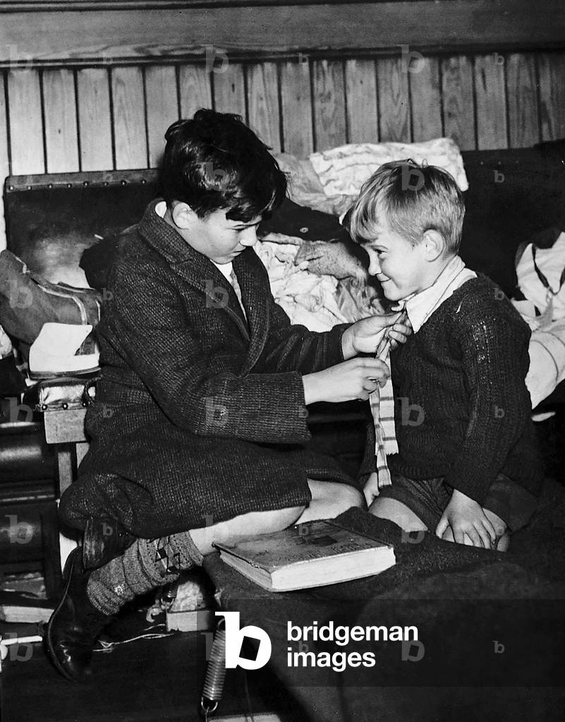 Evacuee boy gets a helping hand from his elder brother, 1940 (b/w photo)