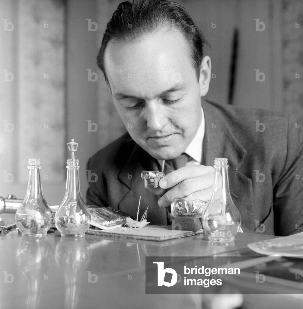 Man creating a ship in a bottle model: 1965 (b/w photo)