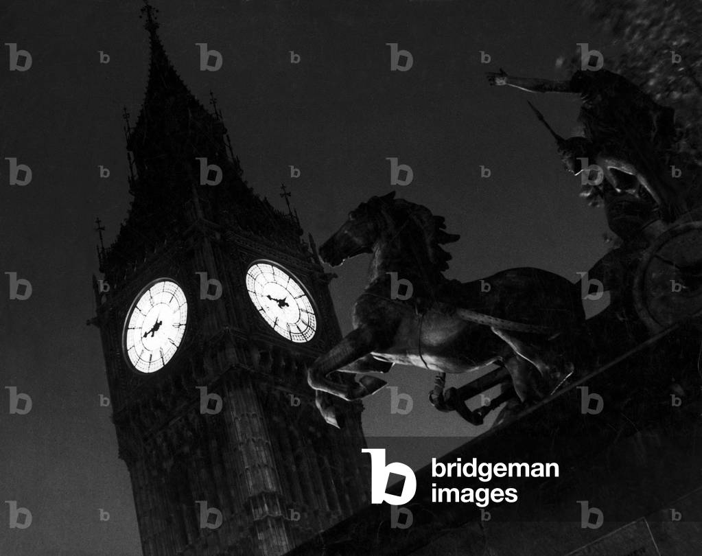 The statue of Boudicca (Boadicea) Queen of the Iceni, driving a chariot by Thomas Thorneycroft and positioned at the end of the Victoria Embankment in 1902. Boudicca led a revolt against the Romans in 61 AD. In the background is the clock tower of the Houses of Parliament which houses the clock and 13-ton bell known as Big Ben. The clock, designed by Sir Edmund Beckett, and bell is named after Sir Benjamin Hall, who was Commissioner of Works at the time of their installation in 1859. 16th November 1938 (b/w photo)