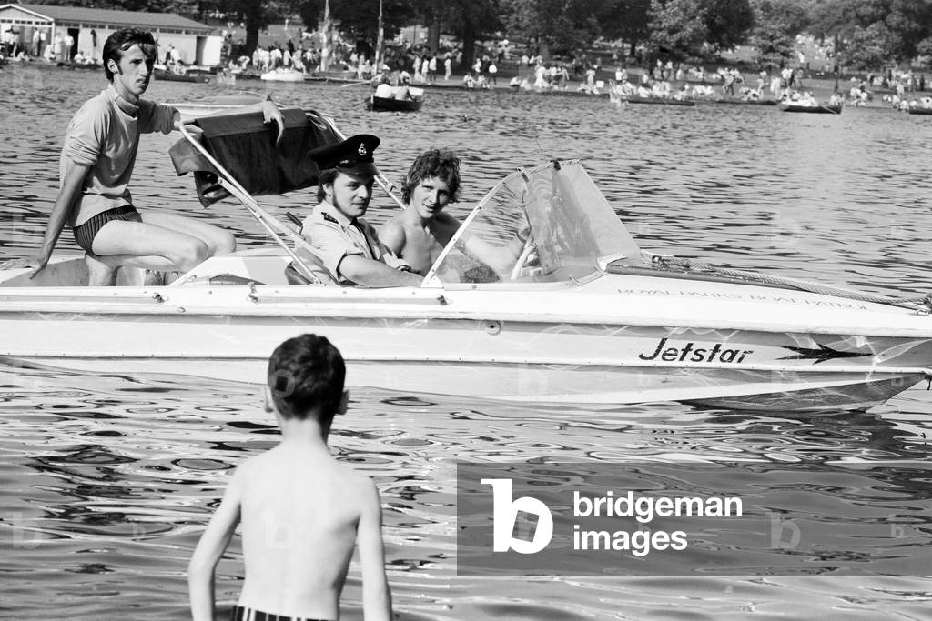 The coolest PC in London's 86 degree heatwave, patrolling his beat on the Serpentine, Hyde Park, in a speedboat. London. 11th July 1971 (b/w photo)