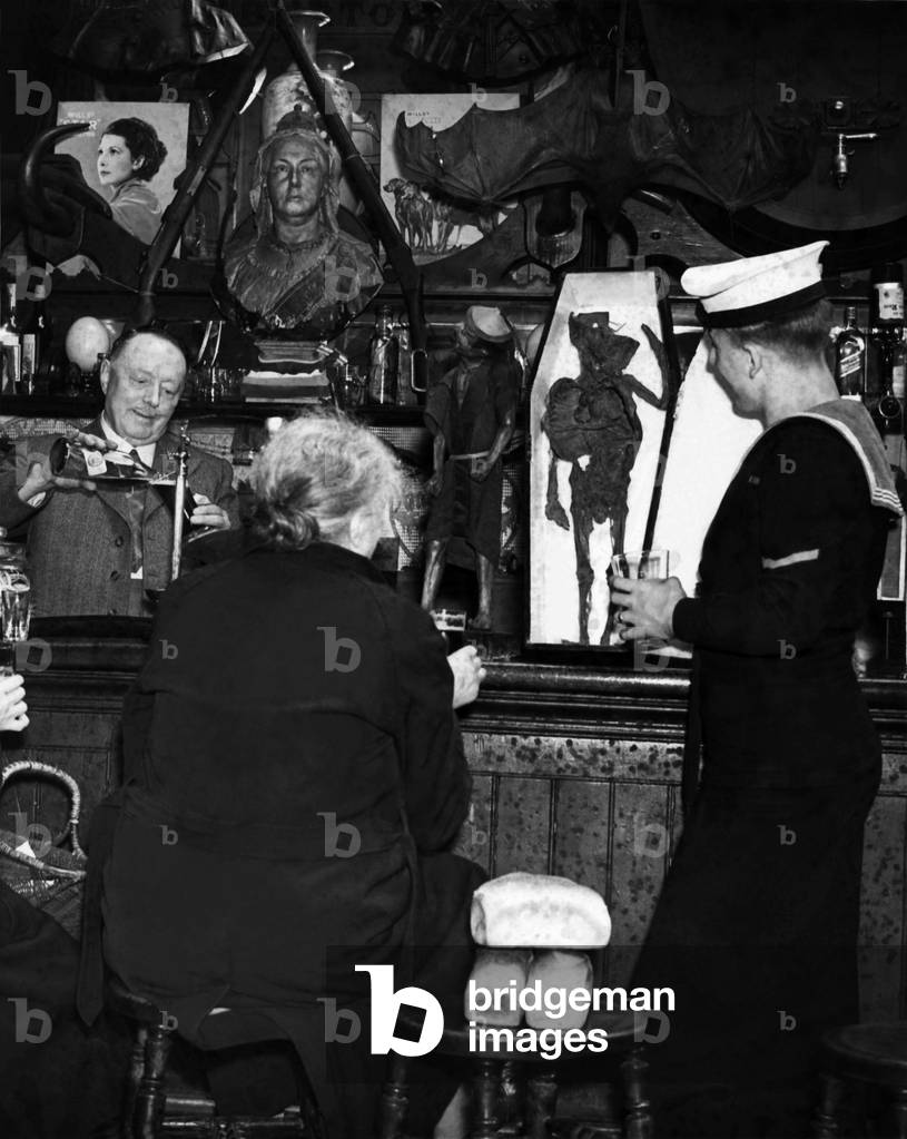 Sailor Dennis Allen and Marine John Sheppard, with housewives, drink amongst the museum pieces. Whilst Bert Lingwood is behind the bar. August 1946 P000071