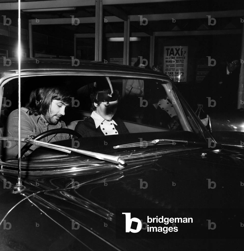 George Best and Carolyn Moore: George Best prepares to make his dash from Wilmslow railway station with his girl-friend Carolyn Moore. She had travelled from Crewe by train, January 1972 (b/w photo)
