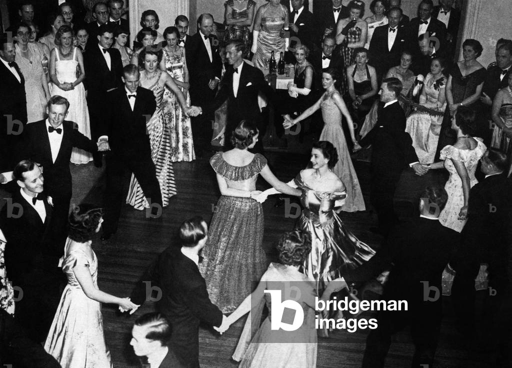 Princess Elizabeth dances arms linked with Lady Pamela Mountbatten and the Duke of Edinburgh during an eightsome reel at The Saddle Club Dance, Malta, 1940 (b/w photo)