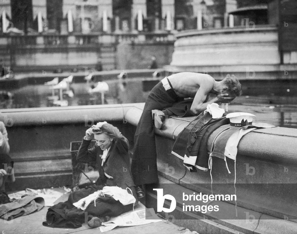 These young women and a sailor appear to have slept out in Trafalgar Square in preparation for the VE Day celebrations, 8th May 1945 (b/w photo)