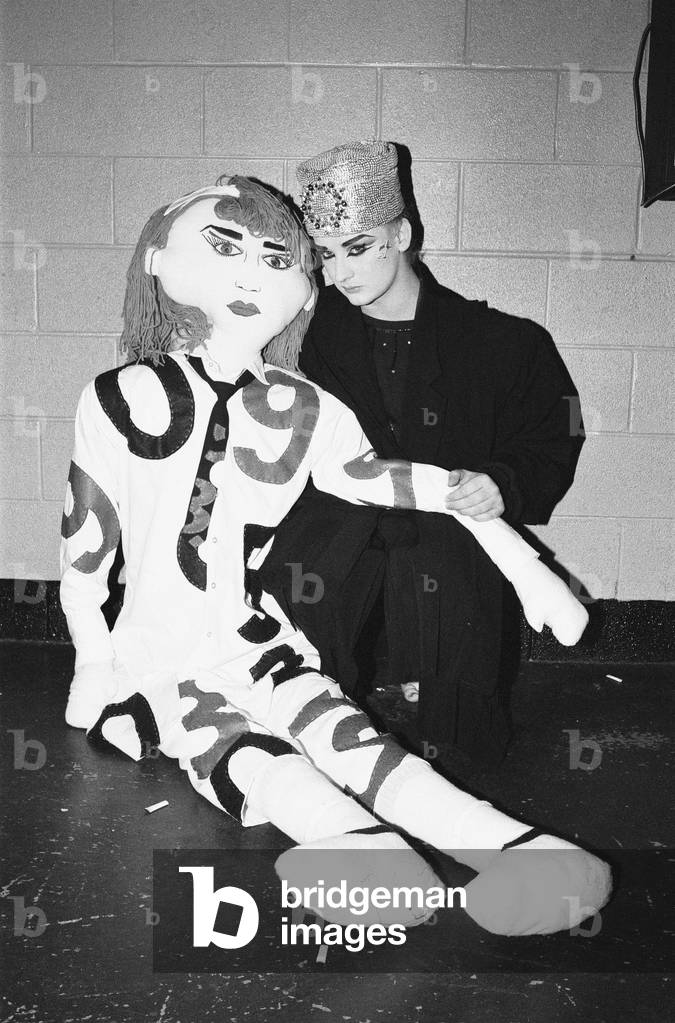 Lead singer with the band Culture Club, Boy George seen here with a 'Boy George' doll back stage at the Rosemont Stadium, Chicago. 11th November 1984