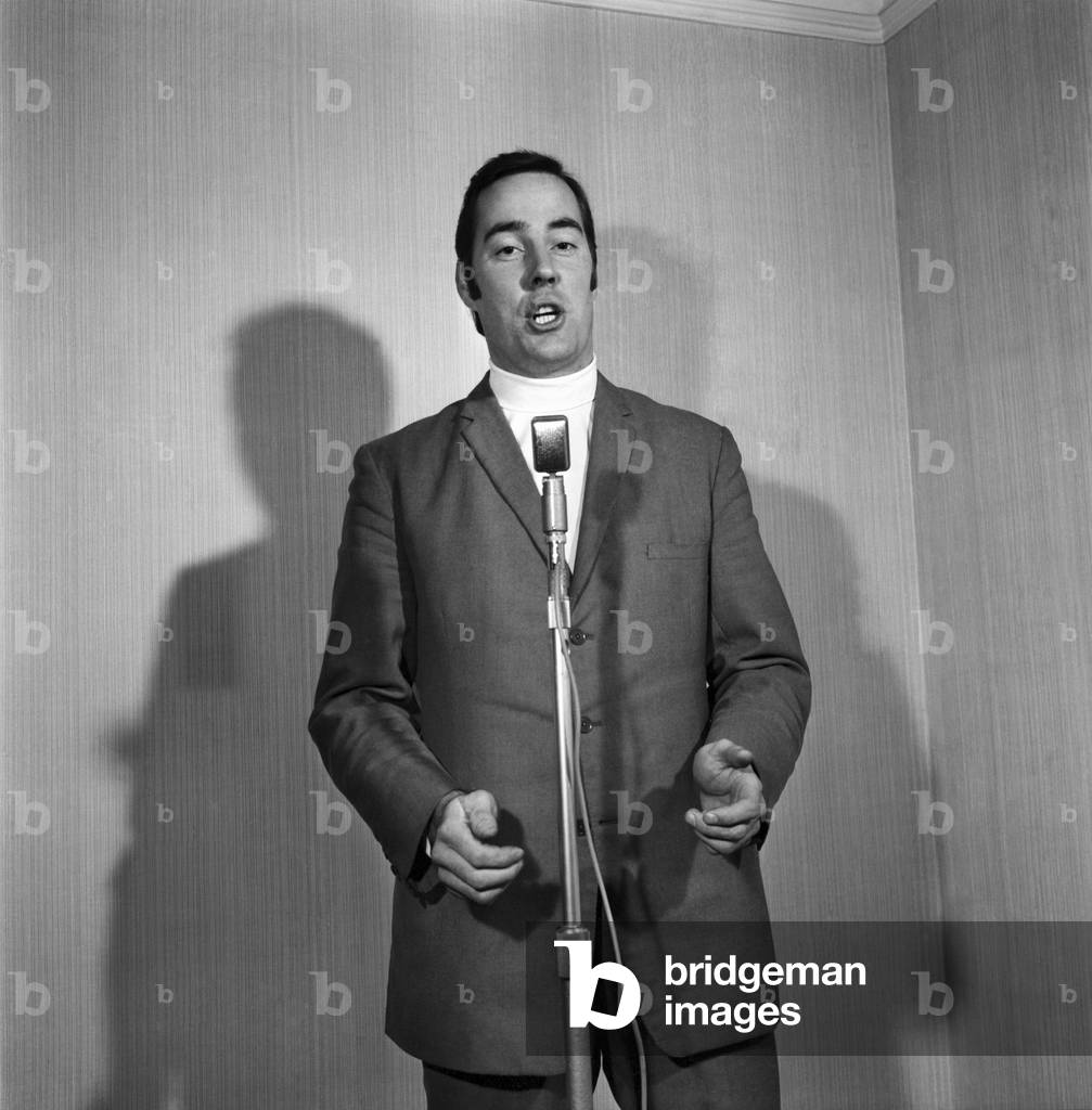 A man wearing a suit singing into a microphone. November 1969