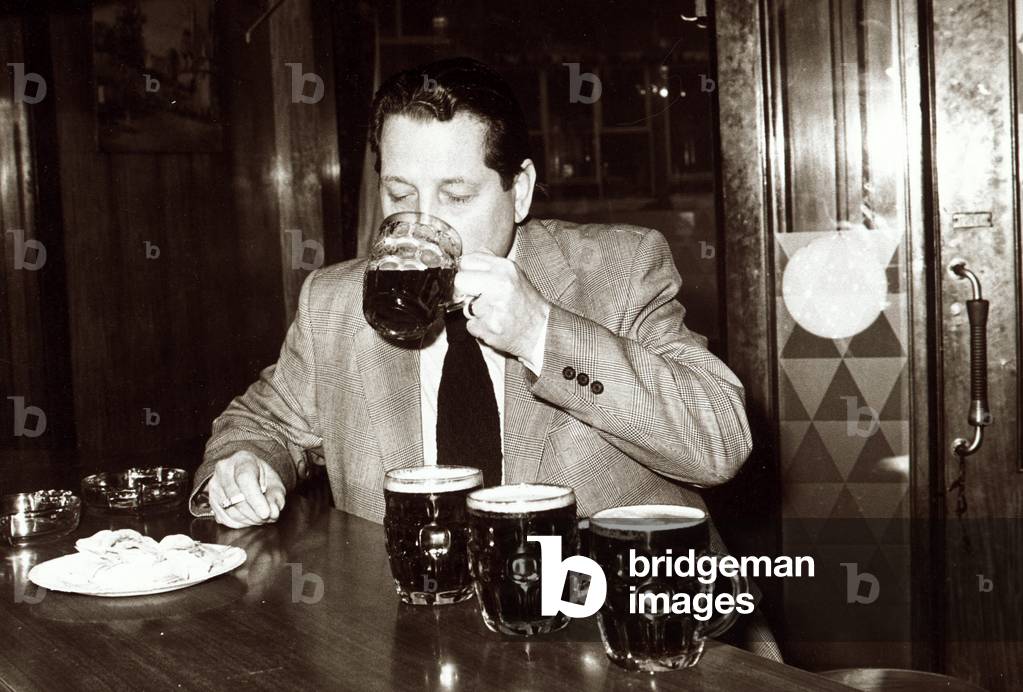 Man in pub drinking several pints of beer which are lined up on the bar ready
February 1979