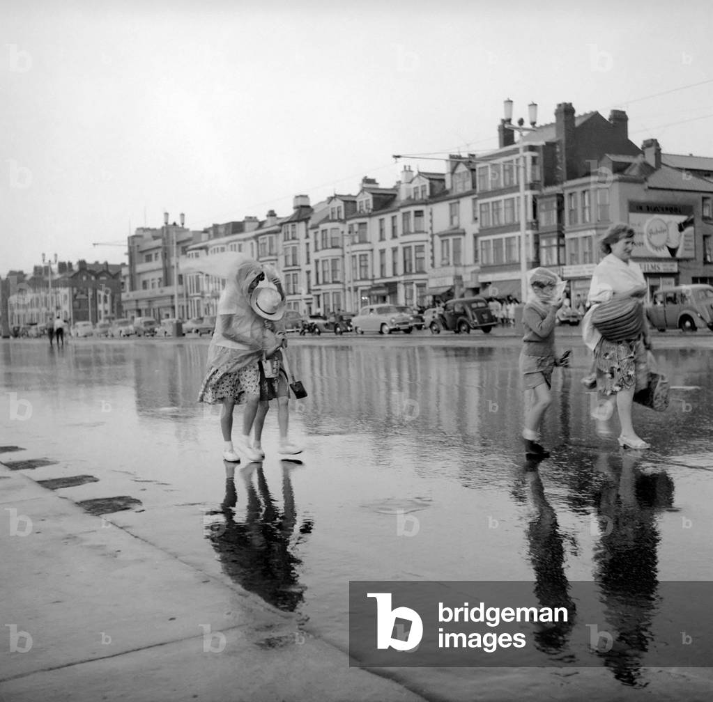 Blackpool after the storm. A couple of young holiday makers make their way off the beach along the promenade.
