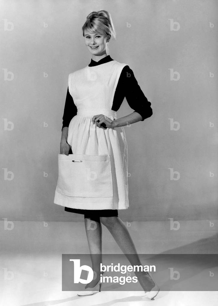 Jennifer Wilson wearing an apron over her black dress. March 1960