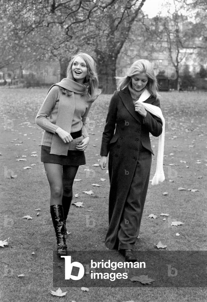Model Blanche Webb wearing mini skirt and knee high boots with model Monica Hahn wearing a maxi coat as they stroll through the park
November 1969