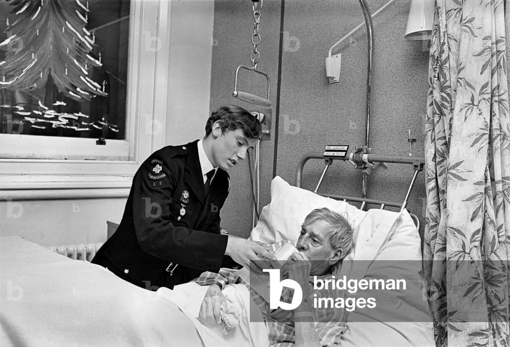 Volunteer Labour in Hospitals. 15 year old Robert Newport helping the Nurse in charge of Ward 3 at East Birmingham Hospital 
 Nurse Margaret Flaherty to attend the needs of patient Mr. David Austin. 
 December 1969