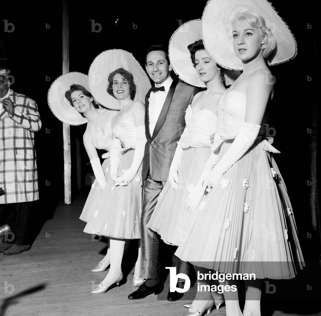 Lonnie Donegan, star of the Palace Theatre show 'Spring Show' which gives the girls of the 'Debutantes' a laugh as he clowns around during rehearsals. 1st May 1962 (b/w photo)