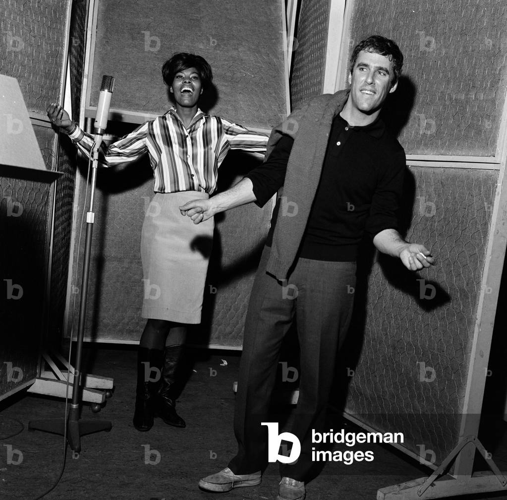 Burt Bacharach and Dionne Warwick recording a song at the Pye studios in London. Dionne sings and Burt directs and dances to the tune. 29th November 1964 (b/w photo)
