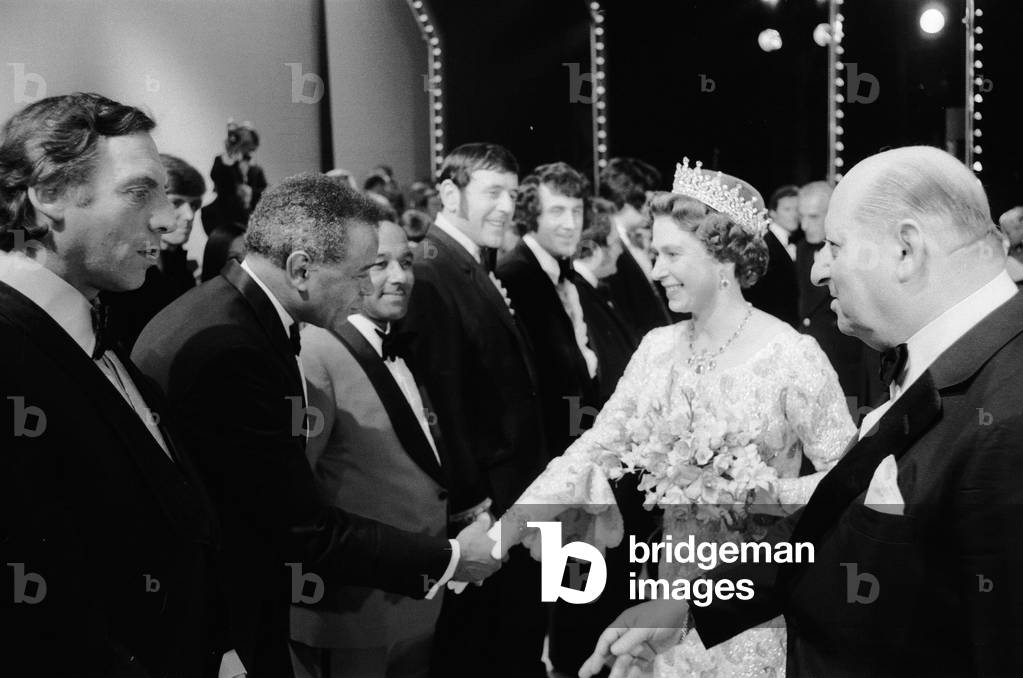 Her Majesty Queen Elizabeth II, escorted by Media mogul Lew Grade (right), shakes hands with stars at the Royal Gala Variety Performance at the London Palladium in aid of the British Olympics Appeal Fund, 22nd May 1972 (b/w photo)