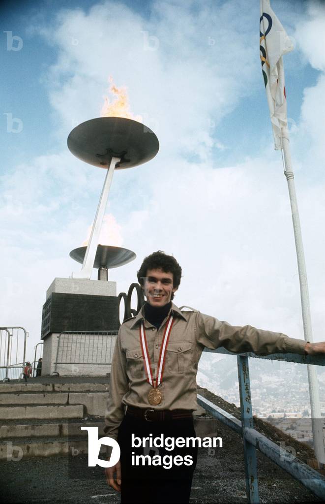 John Curry Ice Skater with his Olympic Gold medal February 1976 at the 1976 Winter Olympics. Standing in front of the Olympic torch