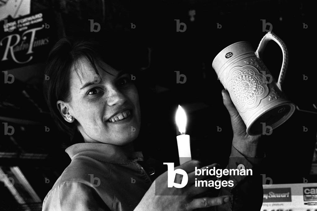 A shop assistant in Newcastle works by candlelight during the power cuts, 07/01/1970