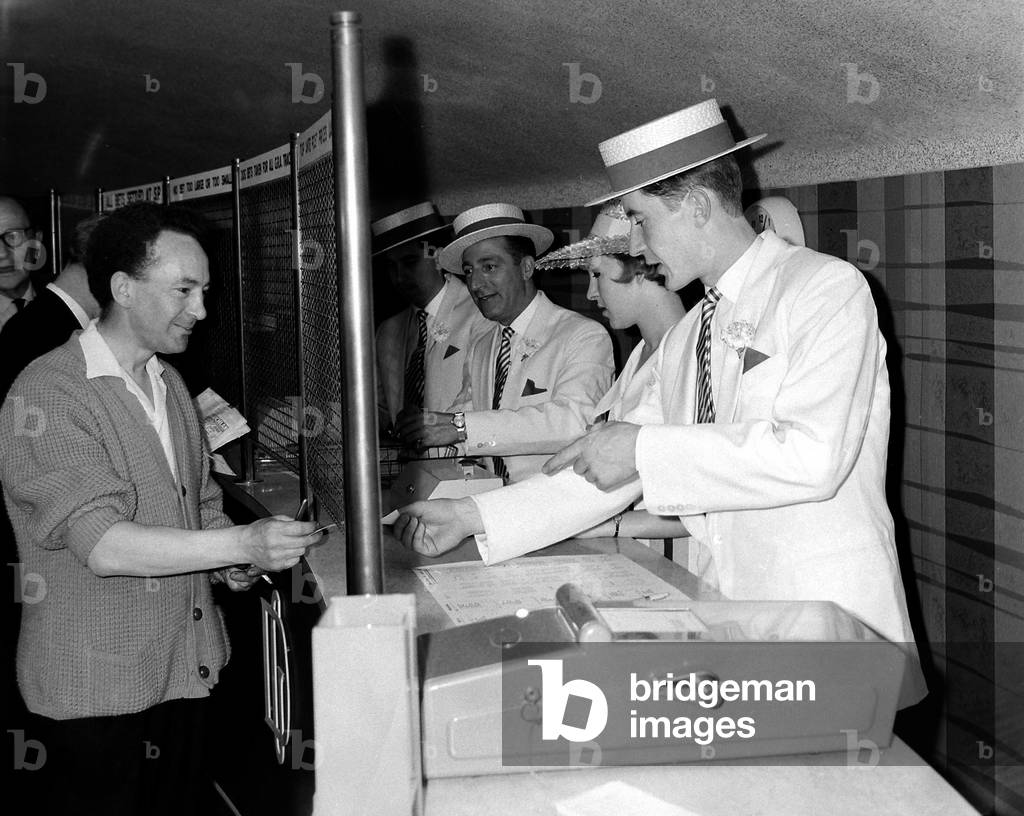 Counter clerks decked out in clothes to match the mood of the meeting at Goodward as they serve punters at a betting shop in Manchester
August 1963