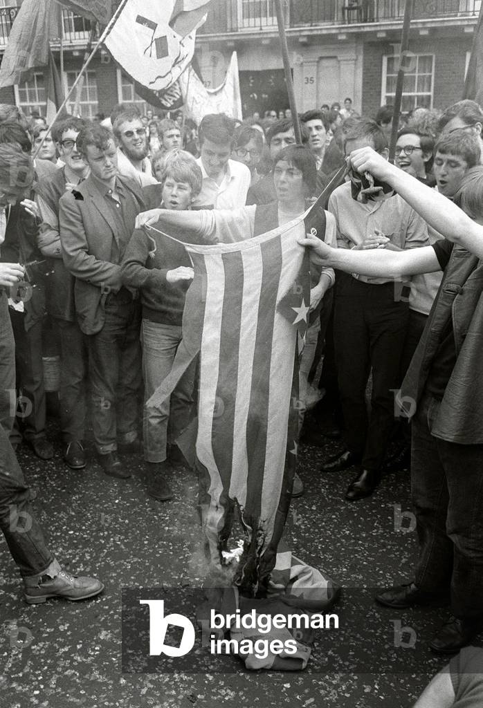 A fringe element from the Vietnam peace rally burning the American flag (Stars & Stripes) in Grosvenor Square, 21/07/1968 (b/w photo)