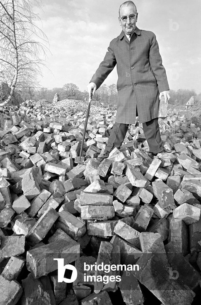People - elderly. An old man searching through a pile of bricks. December 1969