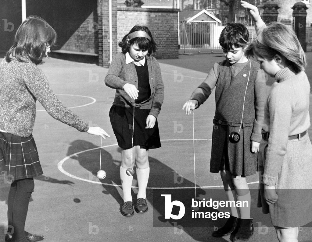 School children playing yoyo games in the school yard. March 1967