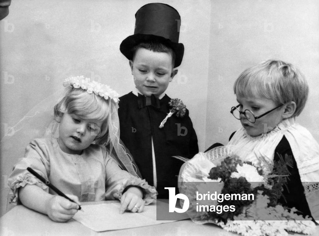 Tiny Tots at Bluebell Nursery at Huyton, Liverpool, took part in a mock wedding ceremony yesterday. Bride Helen Smith, 4, and bridegroom, Ian Welsh, 4, face the vicar Stewart Fergie, 4, as they married at the Alter. Young couple sign the register. March 1970 P12091
