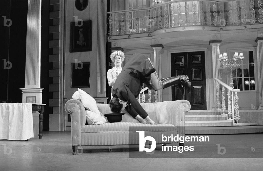 Actor Robert Lindsay in his role as Bill Snibson in the stage musical Me and My Girl at the Adelphi Theatre in London, performs a somersault over the sofa during the performance. February 1985 (b/w photo)