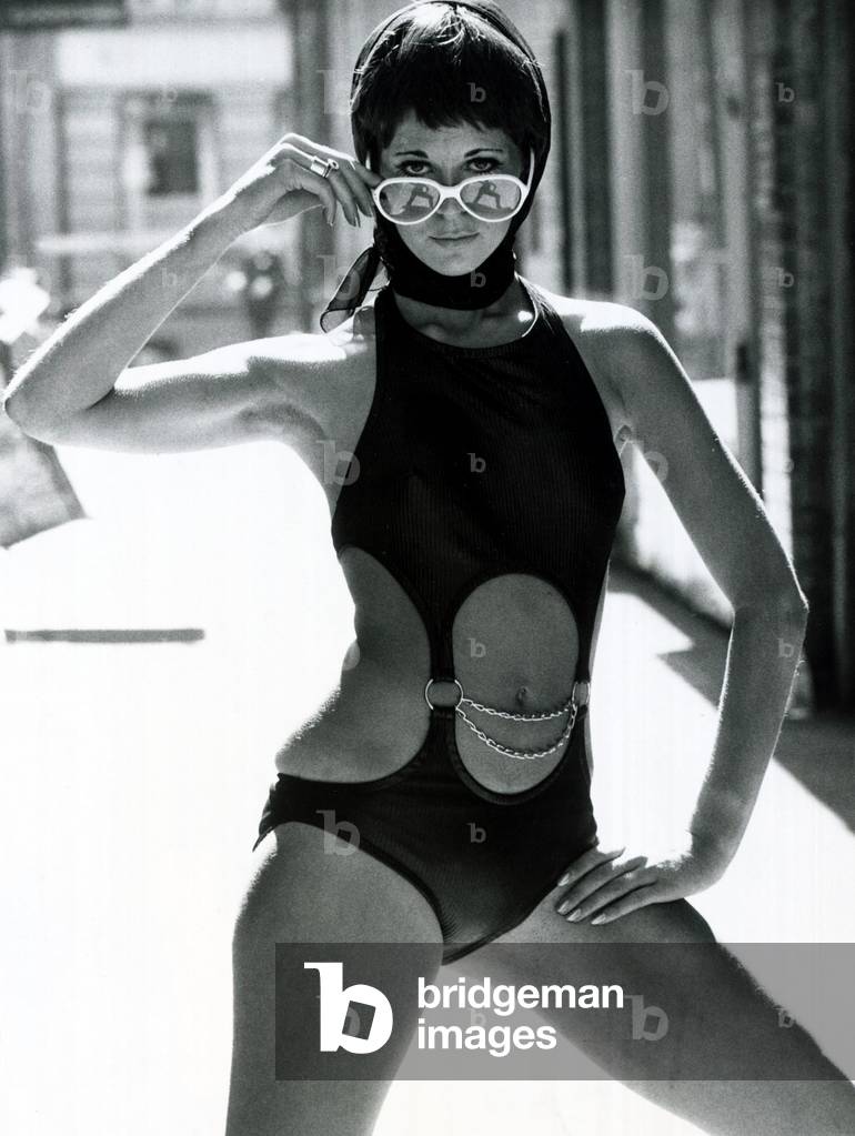 Fashion 1960s Model weaing Black Swimsuit with rings and chains, a black headscarf and Jackie O sunglasses. September 1969 (b/w photo)