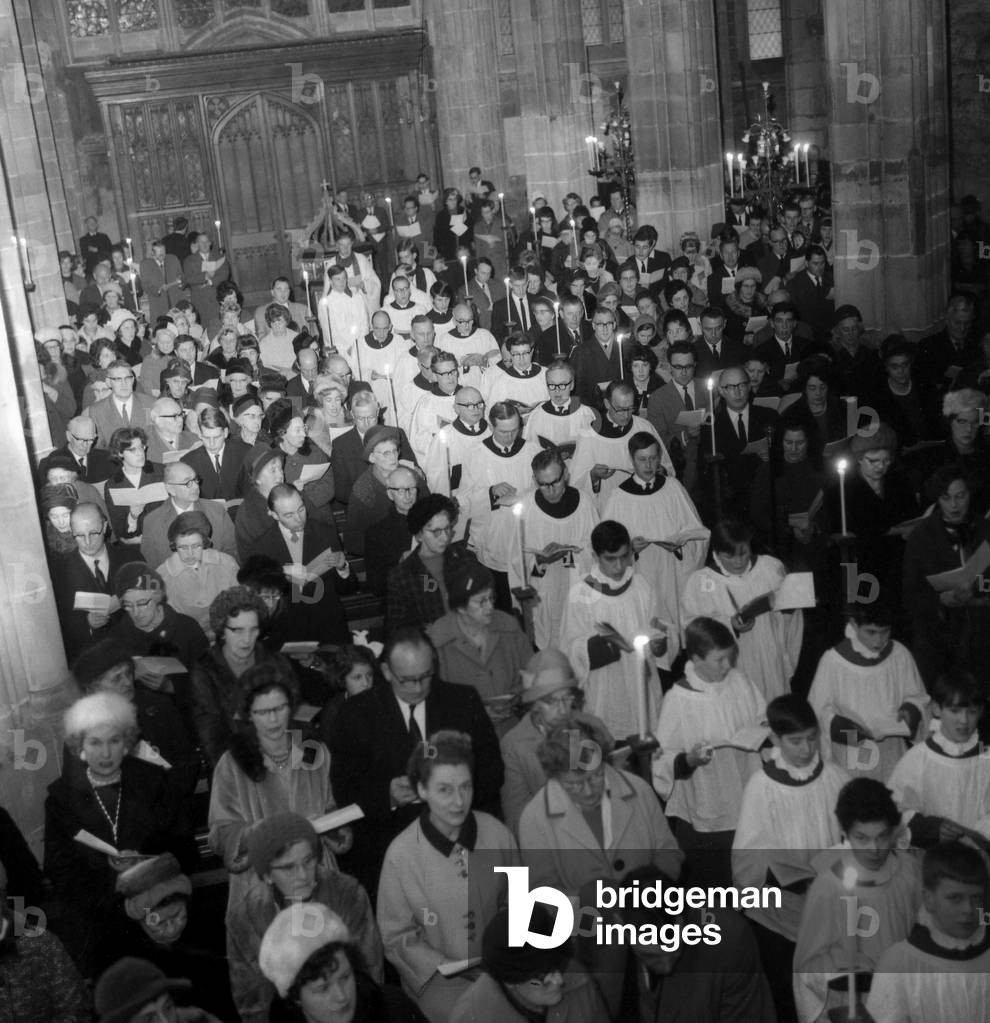 The choir and clergy of Holy Trinity Church, Coventry, walking down the aisle towards the altar during the Festival of the nine lessons and carols held in candlelight 19th December 1965 (b/w photo)