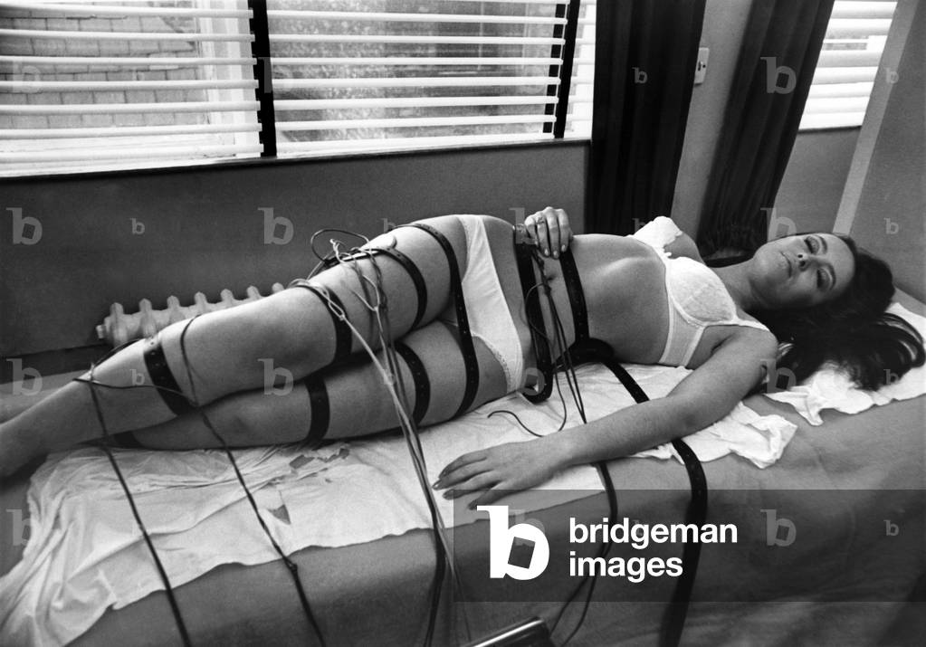 Jeanie Galston, 18, of Blackley, Manchester, rests while the slimming machine gets to work. August 1970