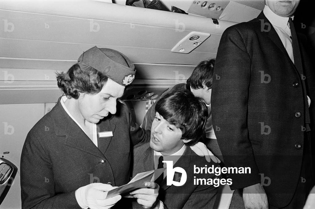 The Beatles in Liverpool for the Premier of a Hard Day's Night. Paul McCartney pictured here talking to a Flight Attendant on the journey to Liverpool for the Premier. 10th July 1964 (b/w photo)