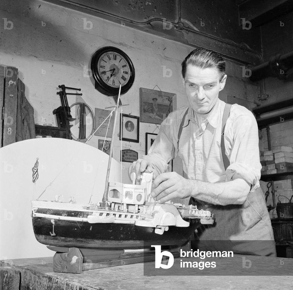 A blind model maker completes his latest model boat 
Circa 1957
