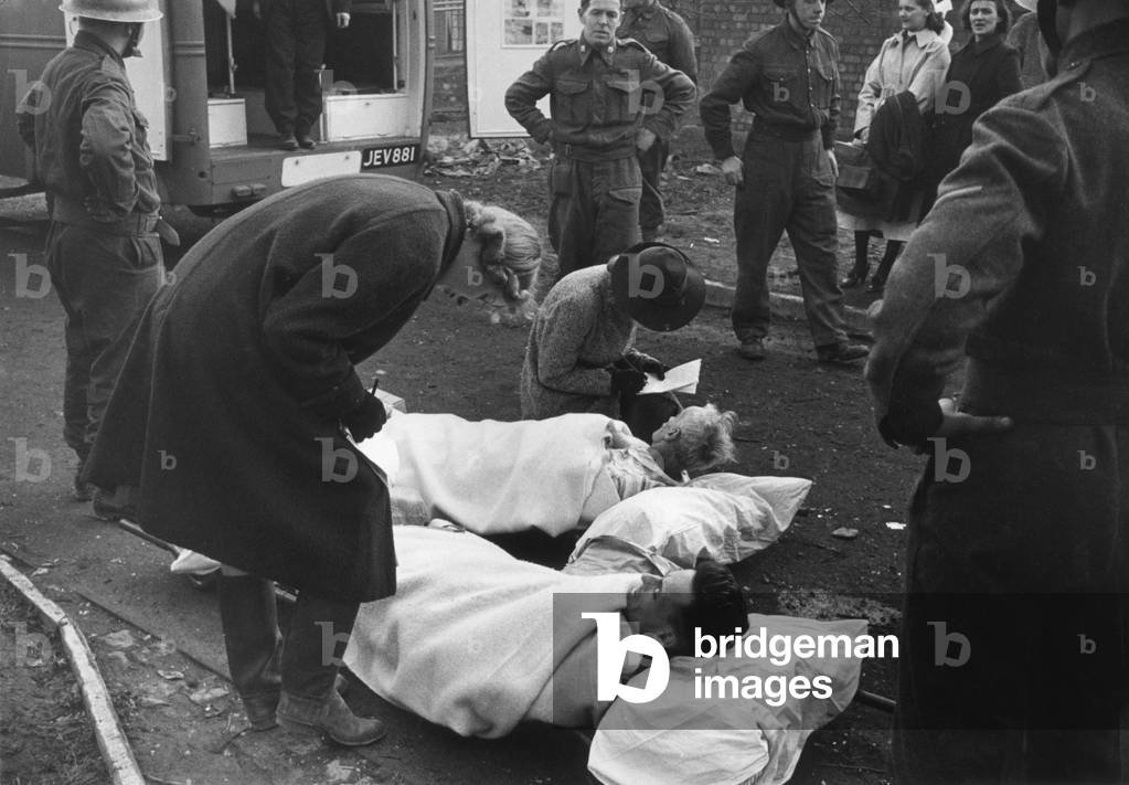 Injured victims attended to by ambulance and rescue workers after an enemy air raid on the city of Coventry in Warwickshire during the Second World War. 
18th November 1940