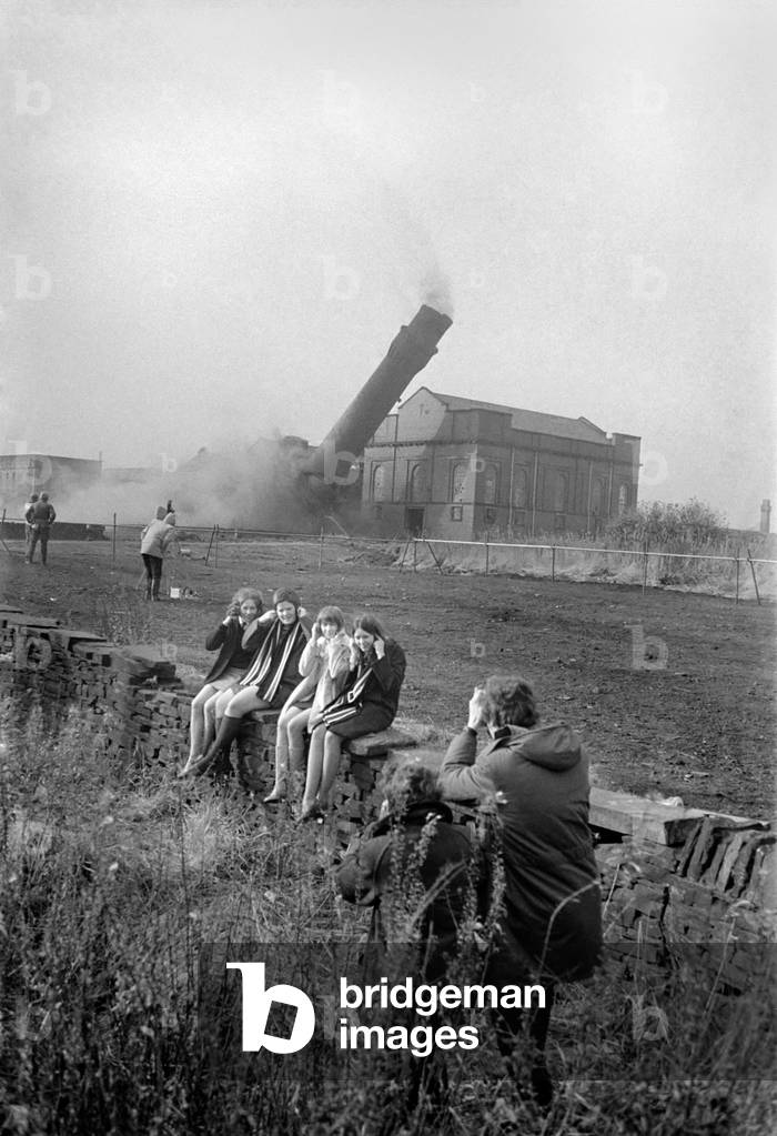 Mill chimneys in Brook Yard, Hipperholme, near Halifax, were demolished. Susan Heviour, Josephine Woodhouse, Ruth Collins, and Patricia Fairbank, fifth form students at Brighouse Heathfield Secondary Modern School, hold their ears as the last crack goes to demolish the biggest chimney of them all. 
October 1969
