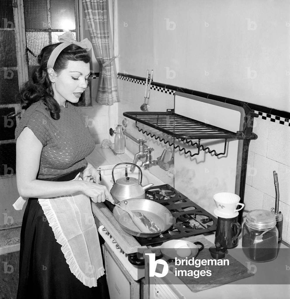 A Housewife cooking in the kitchen, 1957.