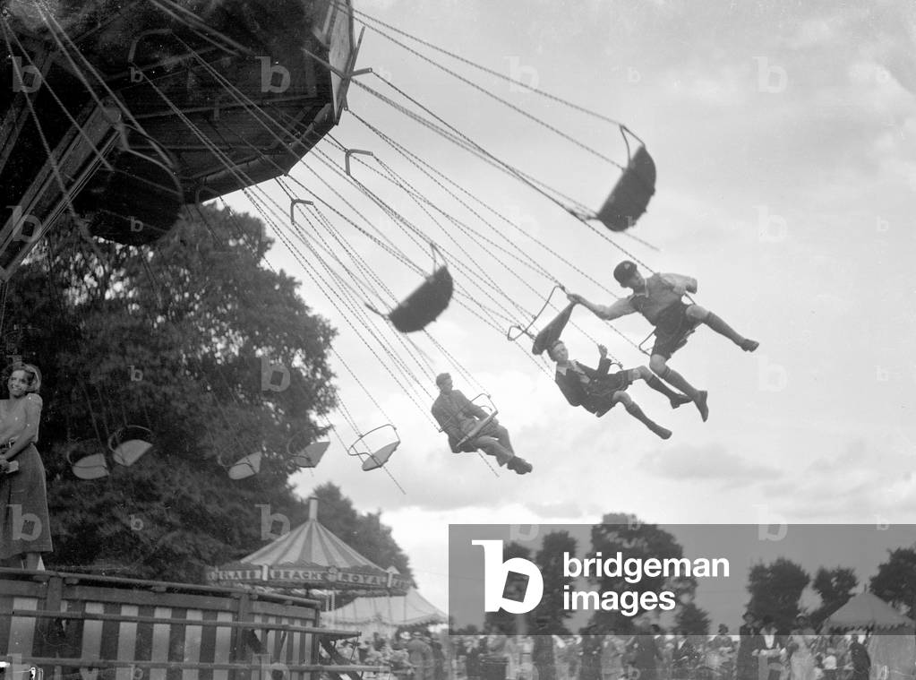 Children ride the Chair-a-Plane ride at the Surbiton fair. Circa 1930