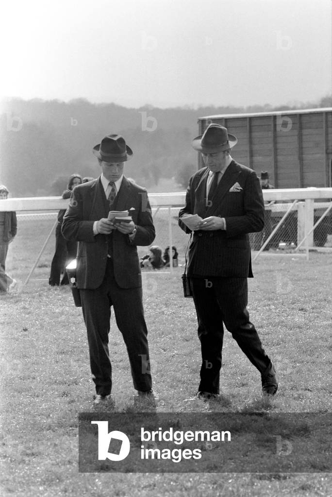 At West Ilsley, Berks trainer Major W. R. Hern stands in front of the 13 horses for the Queen, April 1977 (b/w photo)