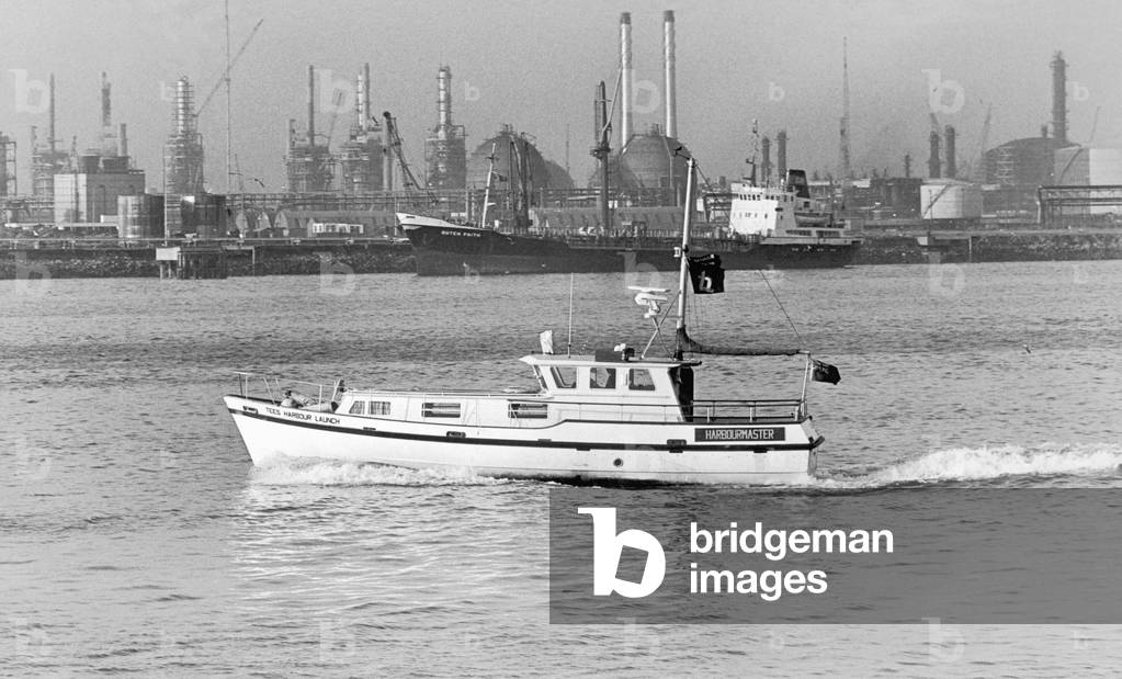 The new Tees Harbour Launch on a daily patrol to check bouys; lights; installations and detect debris. Seen here passing the coastal tanker Dutch Faith and The Phillips - Norway oil complex. 21st January 1977 (b/w photo)