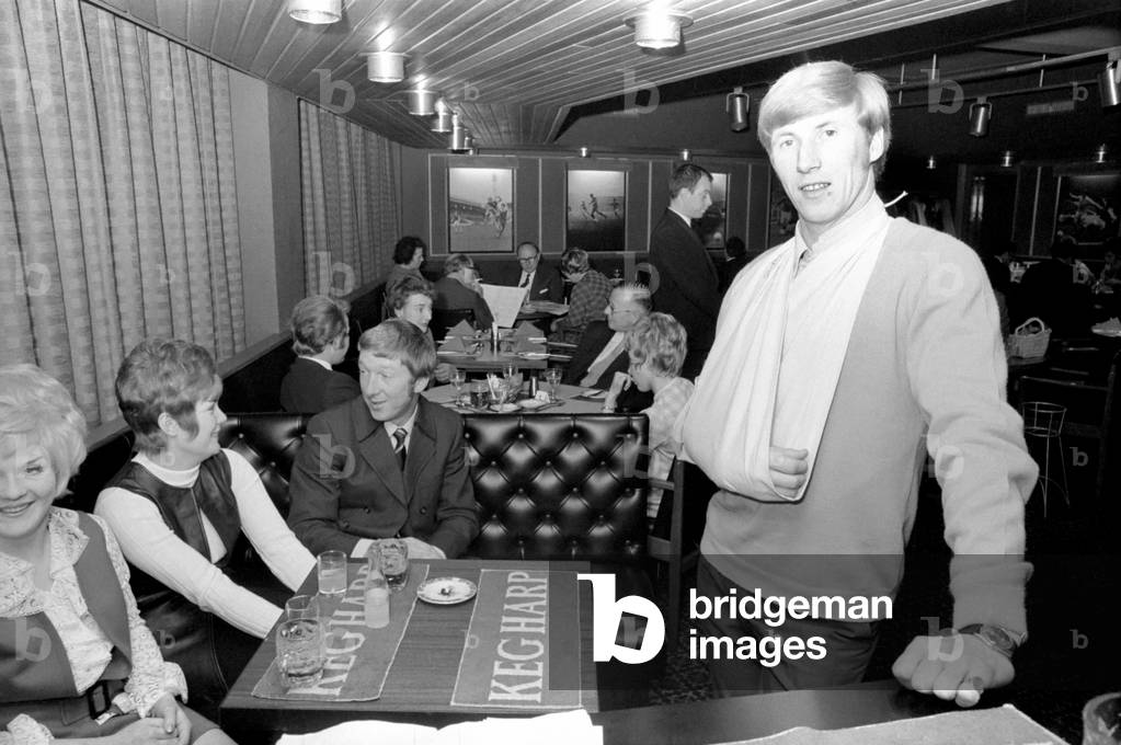 Manchester City and England star Colin Bell nursing his damaged shoulder, injured in Wednesday night's International match, at his Whitefield, Lancashire restaurant with a friend. December 1969 (photo)