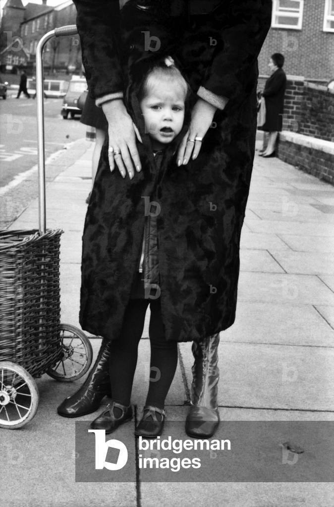 actress Francis Dean who lives in Fairfax Road, N.W.6., wears a maxi-coat and it is made of synthetic fur by astraka. She was out today with daughter Belinda (2) and Belinda found maxis very cosy indeed especially with today's weather. They were waiting for a No. 31 bus where the pictures were taken. November 1969